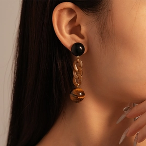 Detail shot of vintage resin chain earrings with tiger eye texture on a fashion model
