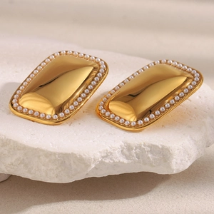 Detail of 18K gold-plated geometric earrings with small pearls on stone background