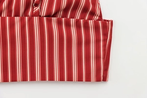 Detail view of red and white vertical striped fabric with metal ring connector and stitching