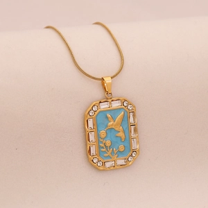 Macro detail of gold hummingbird pendant with blue enamel and sparkling white crystals