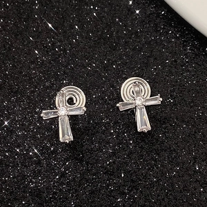 Detail of silver cross clip-on earrings with rectangular cubic zirconia on black background
