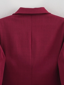 Close-up of burgundy blazer collar and back seam stitching with fine fabric texture