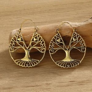 Detailed close-up of vintage gold Tree of Life circular dangle earrings on driftwood