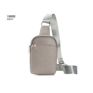 Detail of gray crossbody chest bag showing pebbled leather texture and silver zippers