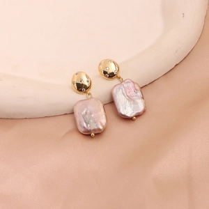 Detail of pink baroque pearls on golden stud earrings with zircons on pink silk