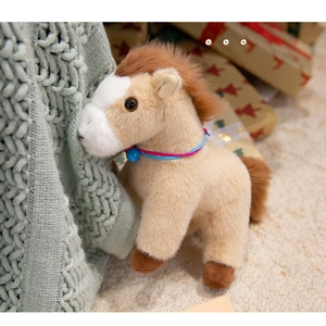 Close-up of beige plush pony toy with brown mane, colorful neck rope and blue bell