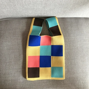 Close-up of knit tote bag with colorful patchwork squares on a soft grey fabric