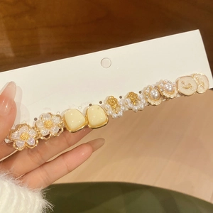 Dettaglio set di orecchini con fiori e perle su cartoncino con finitura dorata vintage