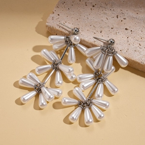 Detailed view of silver flower earrings featuring faux white pearl drops on a stone base