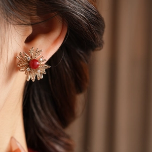 Close-up of vintage flower stud earring with red resin center and gold crystal petals