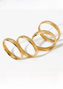 Detail showing set of four gold bangles with intricate floral and star engravings