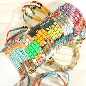 Detail of colorful bohemian enamel Tila bead bracelets with gold accents on a display