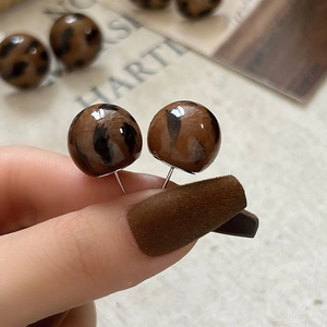 Detail of round leopard print stud earrings with a glossy resin finish for women