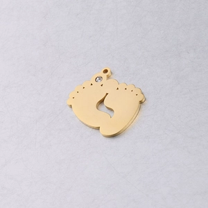 Macro detail of gold stainless steel baby feet pendant with a clear sparkling rhinestone