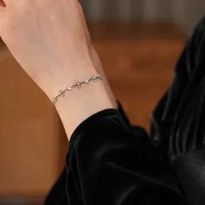 Silver zircon cross bracelet for women styled on a black velvet sleeve background