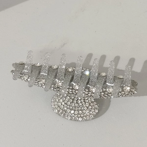Detailed close-up of large silver hair claw clip with sparkling rhinestones on white background