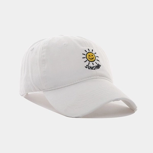 Detail of white cotton baseball cap with yellow sun sunshine embroidery and distressed brim