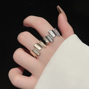 Detail view of gold and silver irregular geometric rings with zircon on model's hand