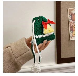 Detailed view of a handmade green crochet Christmas bag with a festive red bow and bell.