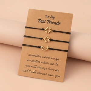 Three sun moon star friendship bracelets on a card with black woven ropes and gold pendants