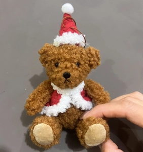 Detail of plush Christmas teddy bear ornament with knitted red hat and festive vest