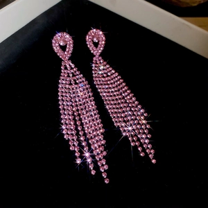 Detail of pink crystal tassel earrings with heart design on a black velvet background