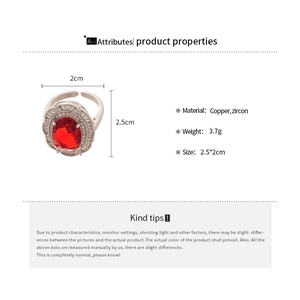 Detail view of luxury open ring featuring oval red zircon and white crystal halo