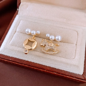 Detail of asymmetrical 18K gold earrings with rocking horse, pearls and crystals