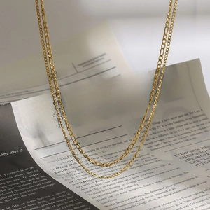 Double-layered 18k gold plated stainless steel Figaro chain necklace on vintage newspaper