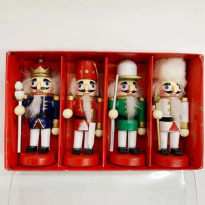 Set of four 13cm wooden nutcracker soldiers with glitter and feather accents in a red box