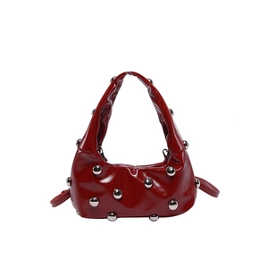 Red patent leather shoulder bag with silver metallic studs on white background