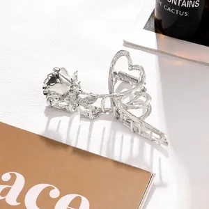 Macro shot of silver metal hair claw clip with carved rose and hollow heart detail