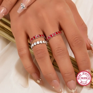 Detailed view of sterling 925 silver rings with red and white enamel hearts on model