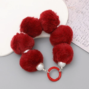 Detail of red plush pom-pom and white pearl beads with a matching red metal ring clasp