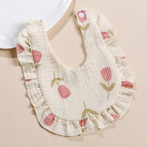 Detail view of cotton muslin baby bib with ruffled edges and pink tulip floral pattern