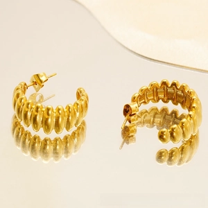 Macro shot of gold ribbed C-shaped thick croissant earrings with textured metallic finish
