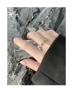 Close-up of a gold ring with textured folds and colorful stones on a hand