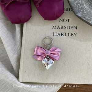 Close-up of pink ribbon bow and silver heart pendant on metal keychain accessory