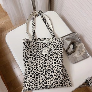 Detailed top view of a leopard print canvas tote bag with a minimalist woven label