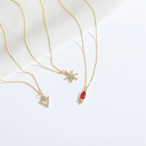 Detailed macro view of three gold necklaces featuring snowflake, triangle and gem pendants