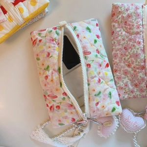 Détail d'une pochette matelassée à fleurs roses montrant sa texture et sa contenance