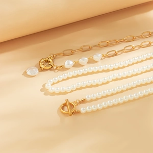 Detail of layered pearl necklace with heart pendant and gold chain on beige background