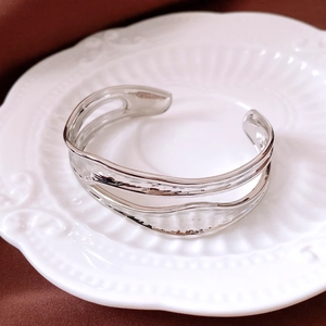 Dettaglio del bracciale aperto in argento a doppio strato su un piatto di ceramica