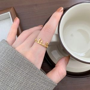 Close-up of golden teardrop crown ring with a melting liquid design worn on a finger