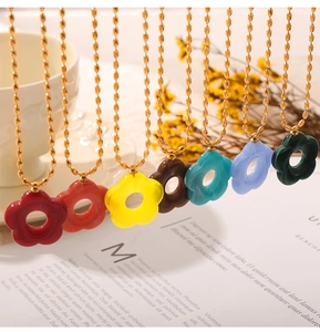 Detail of multiple gold-plated chain necklaces featuring colorful resin flower pendants