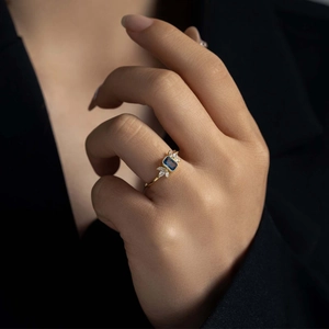 Detail of a gold ring featuring a blue rectangular stone and marquise-cut side diamonds