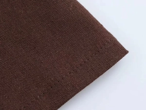Macro del tessuto in lino marrone scuro di un abito a camicia con trama e cuciture
