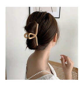 Detail einer großen cremefarbenen Haarklammer, die einen Dutt für einen sanften Look hält