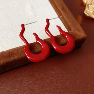 Detailed close-up of red fire-shaped earrings with S925 silver needles on a velvet tray