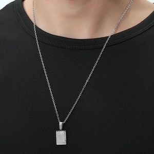 Detailed close-up of a silver sunburst pendant necklace worn on a black casual shirt